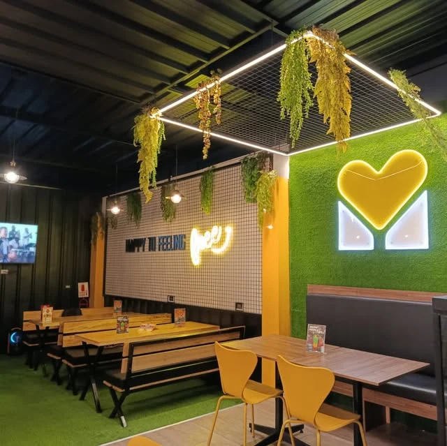 Interior real de la Zona Food de Mía, con mesas, bancas y su corazón amarillo